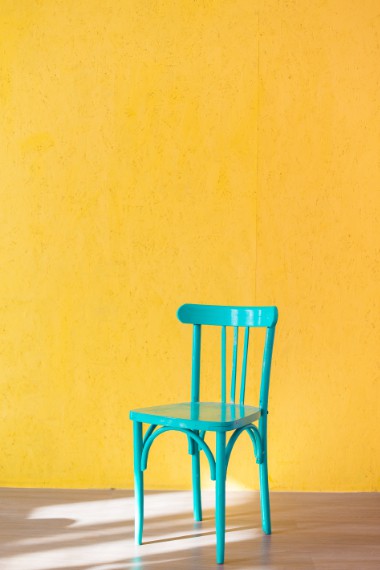 Blue chair against a yellow wall.