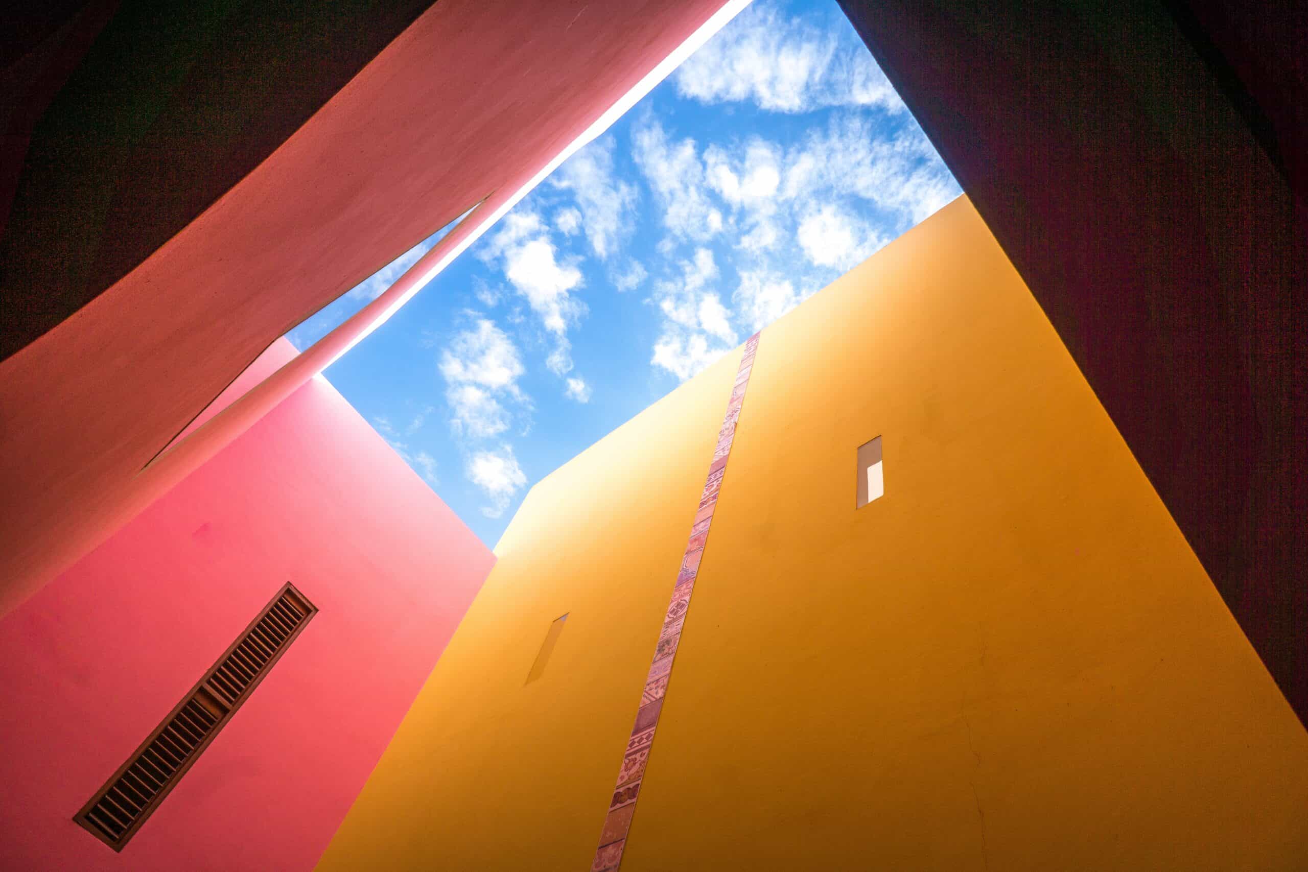 Buildings painted in different colors, looking from below towards the sky.